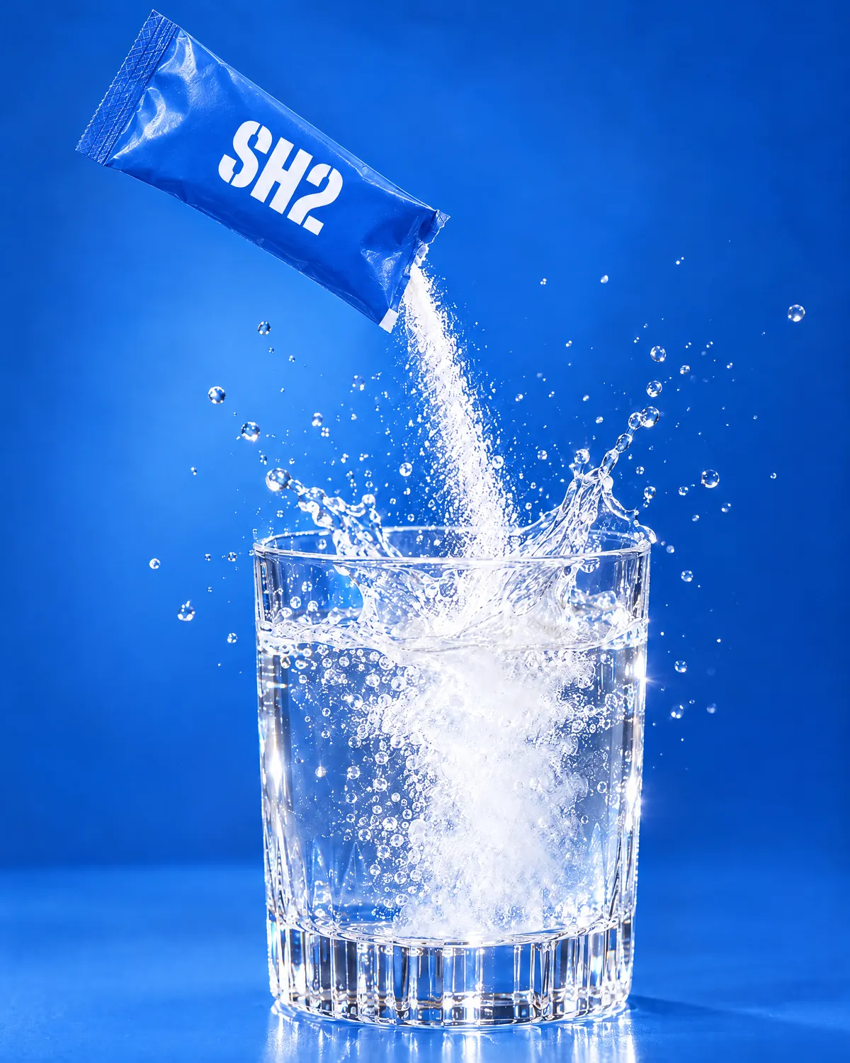 An SH2 sachet pouring its powder into a glass of water