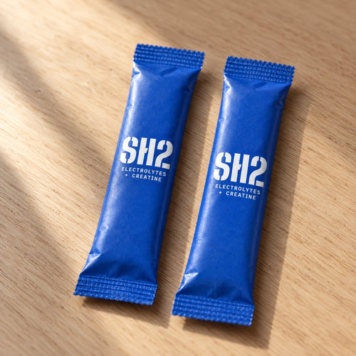 Two SH2 electrolytes + creatine sachets on an oak table